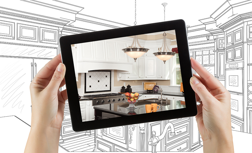 A person holds a photo of their dream kitchen in front of a sketched draft.