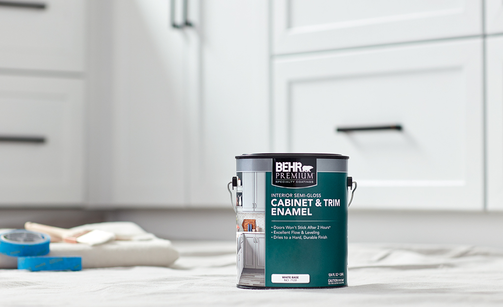 A can of cabinet enamel sits on a drop cloth on a kitchen floor.