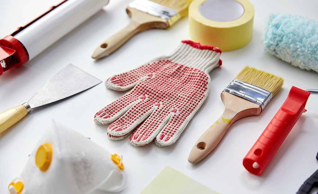 Painting supplies and work gloves are artfully arranged on a white surface.