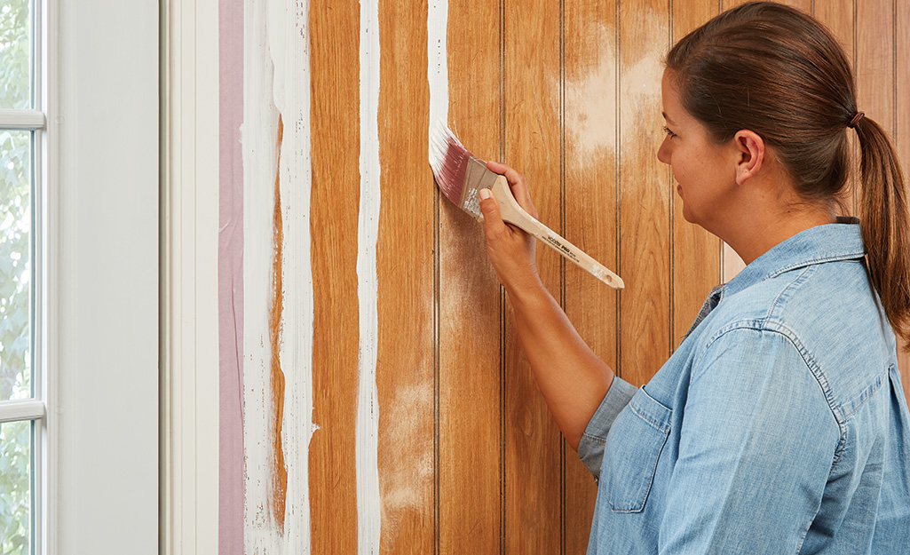 Woman painting paneling with a brush.