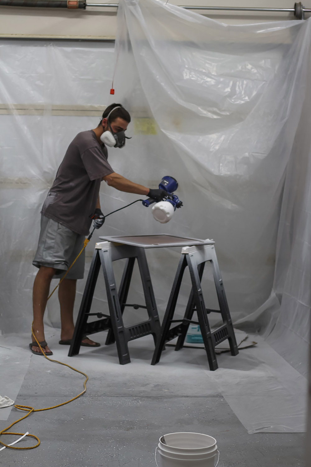 A person painting a cabinet door white
