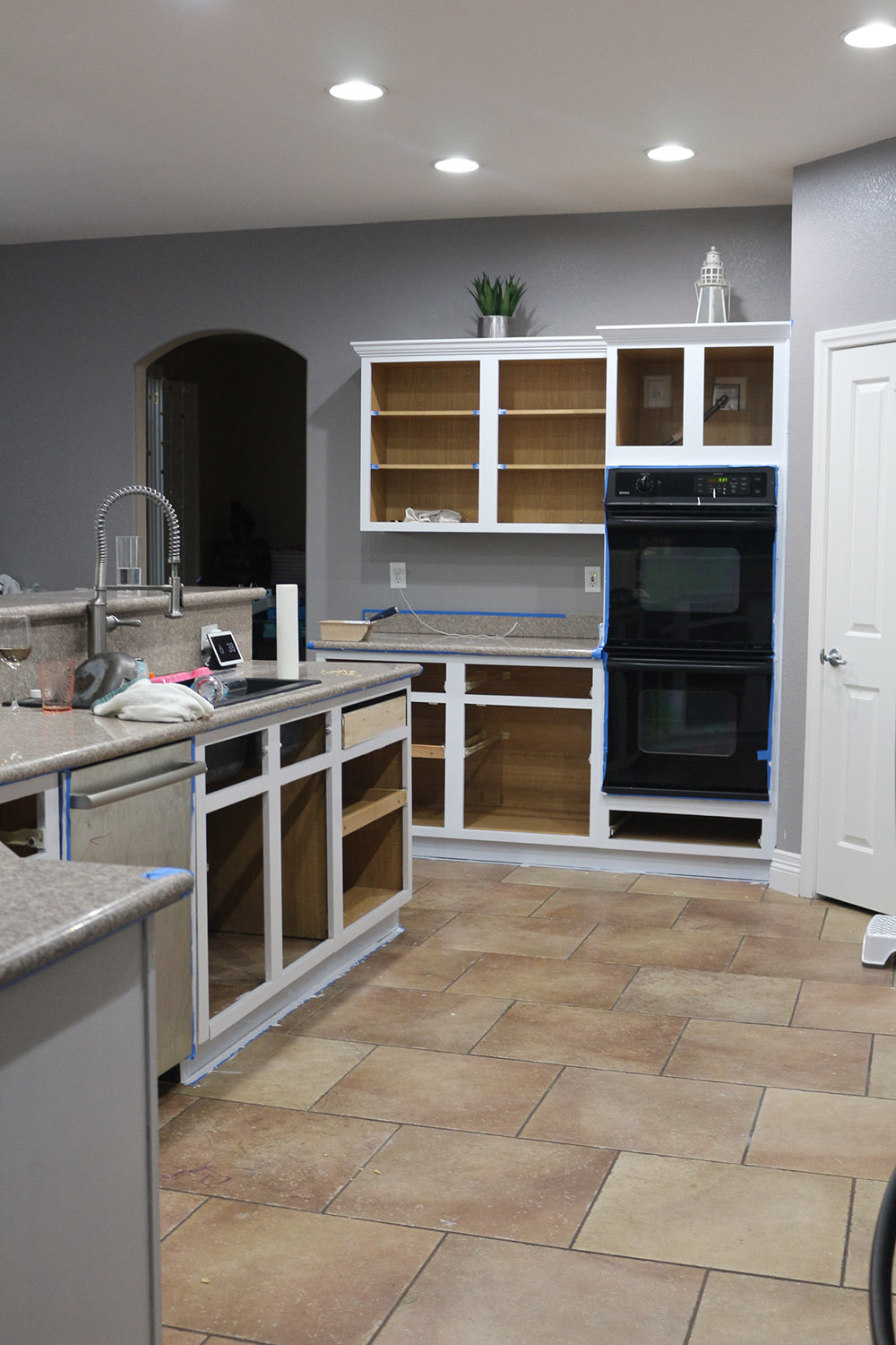 A wide shot of the kitchen cabinets painted white with no doors