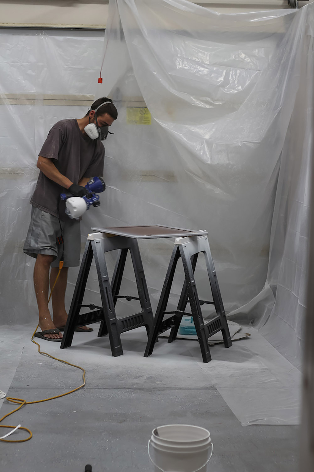 A person spray painting a cabinet door white