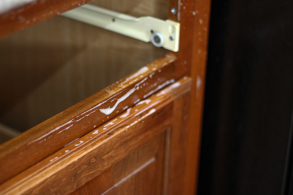 A close shot of brown cabinets being cleaned with soap and water