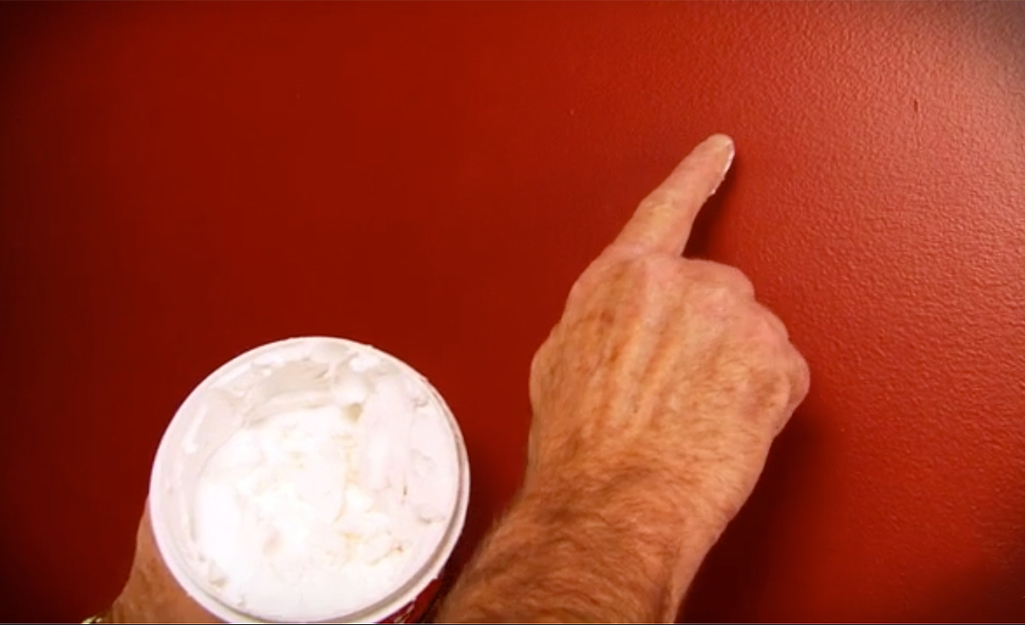 A person applying joint compound to a wall.