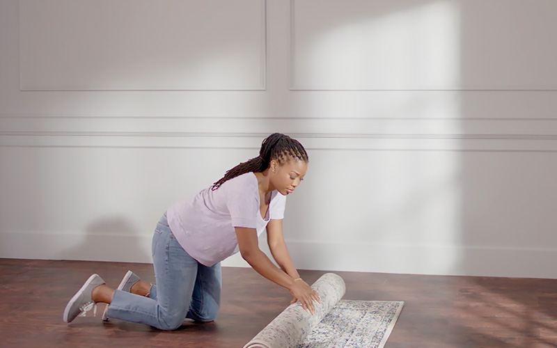 Woman removing rugs in preparation for painting.