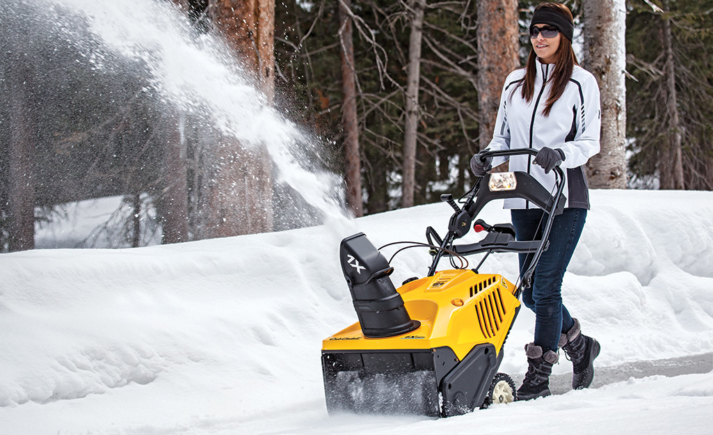 Woman using a snow blower.