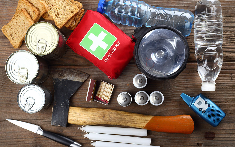 Emergency supplies including a first aid kit and food are arranged on a table.