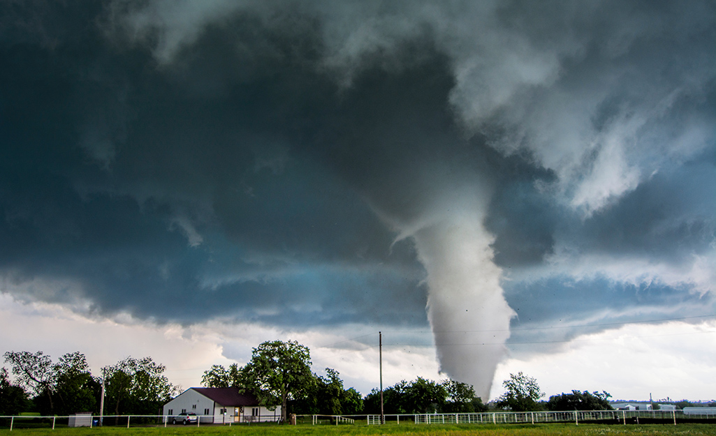 A tornado funnel heading toward a farm house.