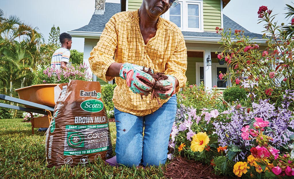 Gardener adding mulch to the flower bed