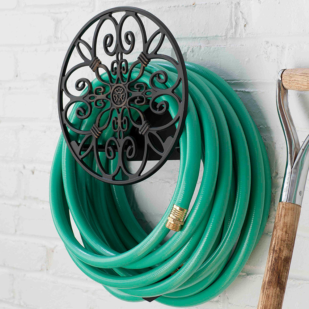 A hose looped around a hose reel on a white brick wall.