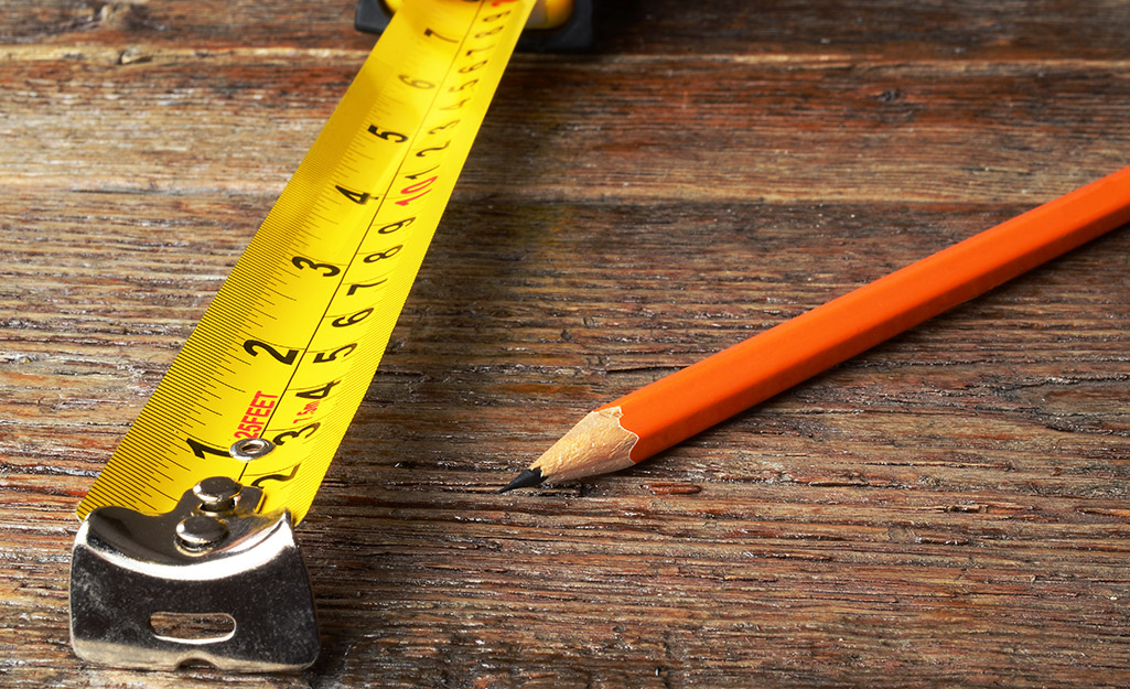 A pencil sitting next to a tape measure.