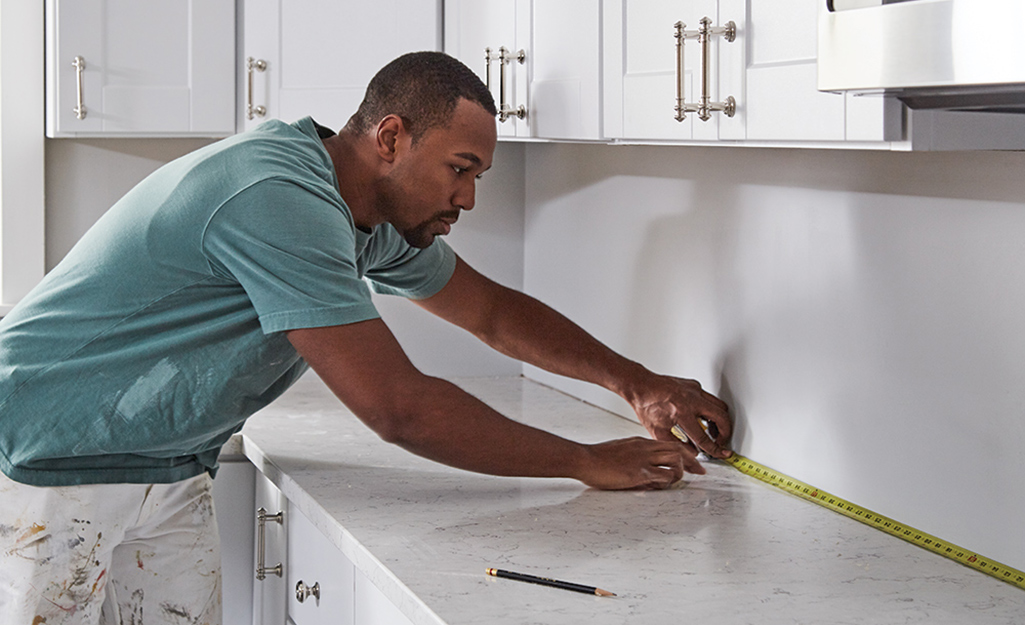 A person measuring a countertop with a tape measure.