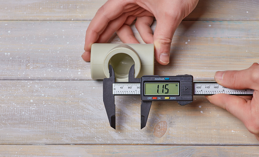 A person uses digital calipers to check the inside dimensions on a plastic part. 