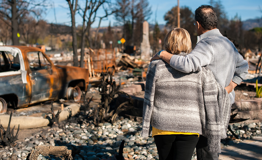 A couple surveying damage from a wildfire. A couple surveying damage from a wildfire.
