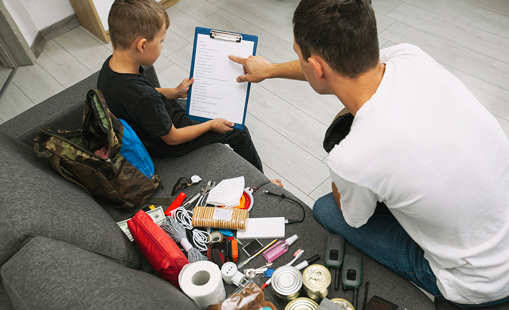 A man and a child with supplies reviewing a disaster checklist. A man and a child with supplies reviewing a disaster checklist.