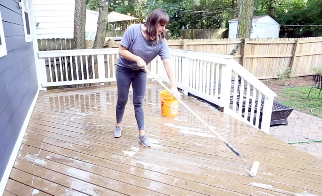 A person cleans a deck with a scrubber.
