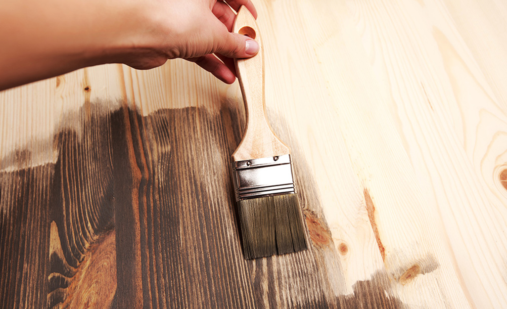 A person applying stain to a piece of wood.