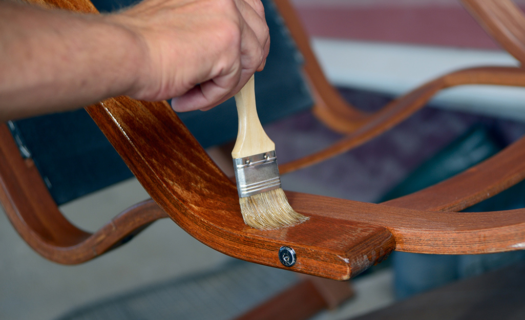 A person applying finish on to a wood furniture piece.