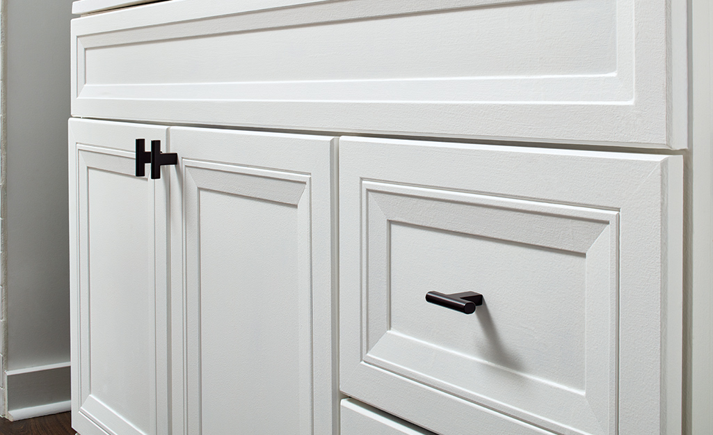 A detail shot of a bathroom vanity shows cabinet hardware and a drawer pull.