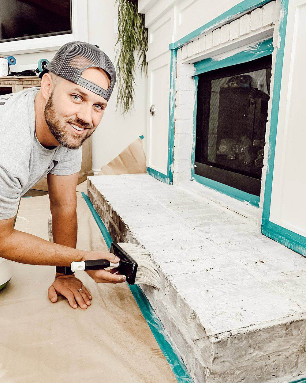 A man smiles for the camera while applying classico limewash to a brick fireplace.