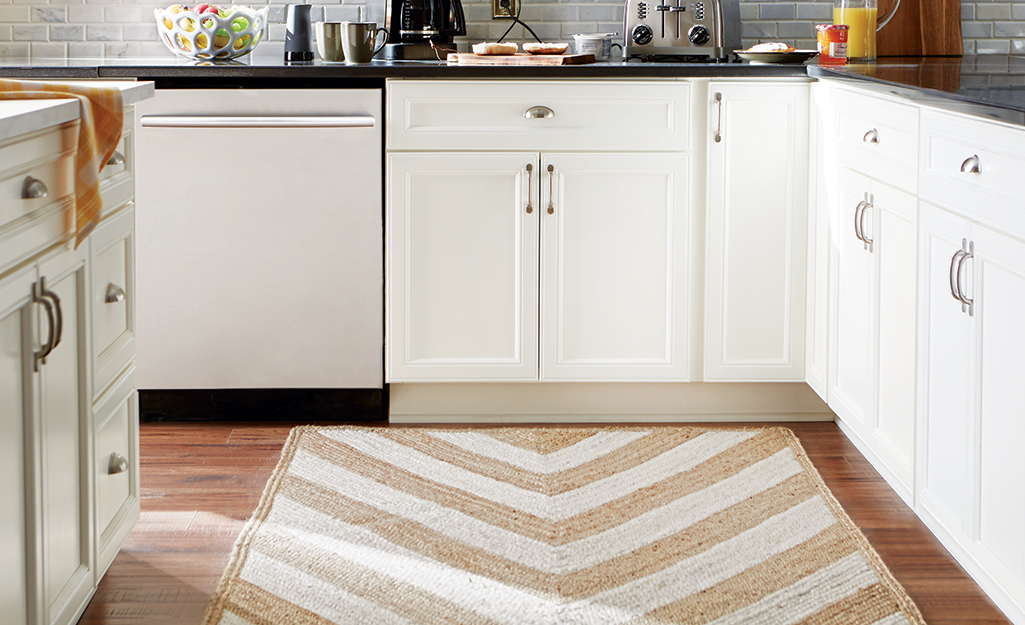 A beige and tan chevron-stripe rug placed in a kitchen.