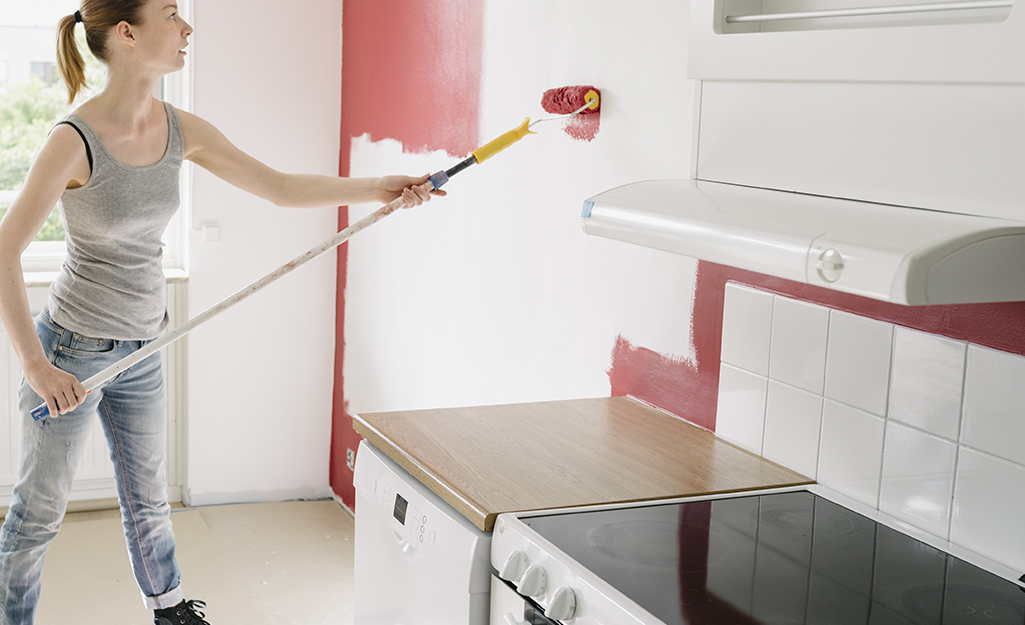 Woman painting an accent wall in a kitchen.
