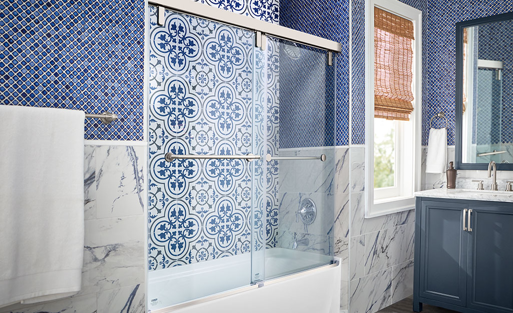 A glass shower featuring a blue and white tile treatment.