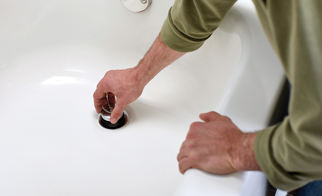Person replaces bathtub drain