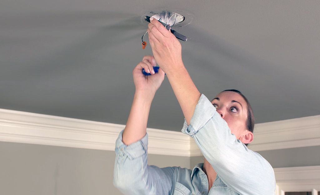 A person detaches the mounting bracket for a ceiling fan.