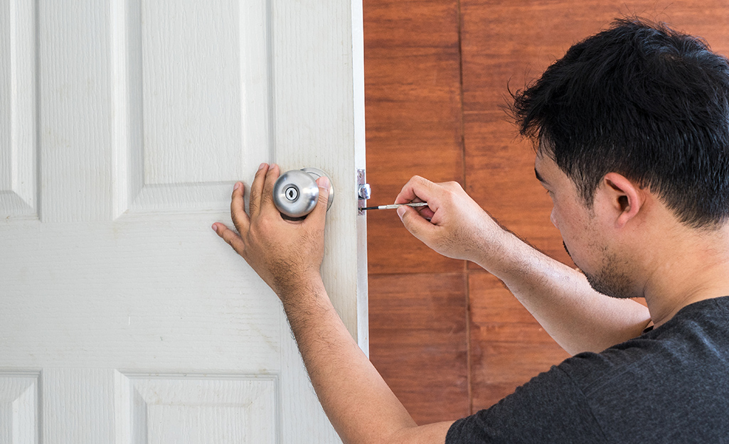 A person getting ready to remove a door knob.