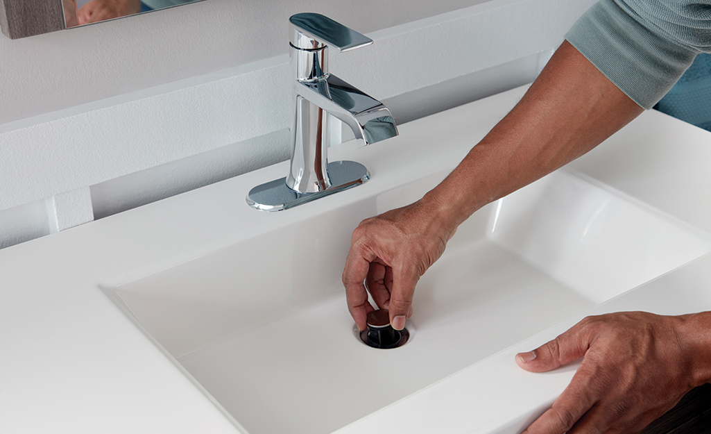 Close up of a white sink with a closed sink stopper.