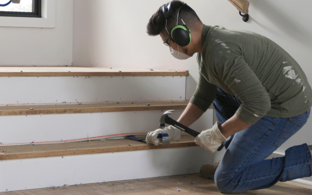 a man removing tack strips from a stair