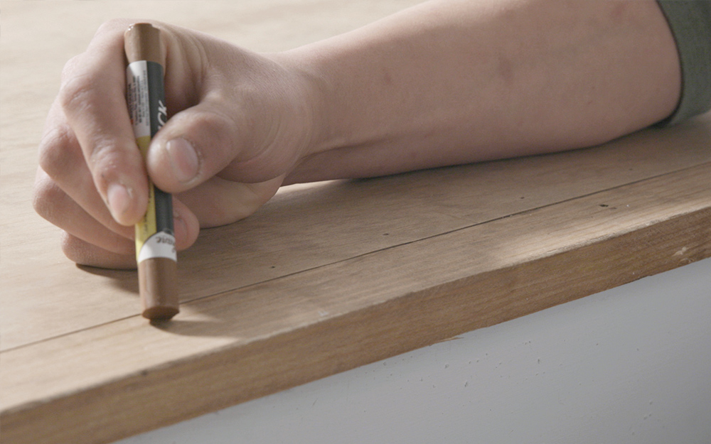 a man filling in holes using a wax stick