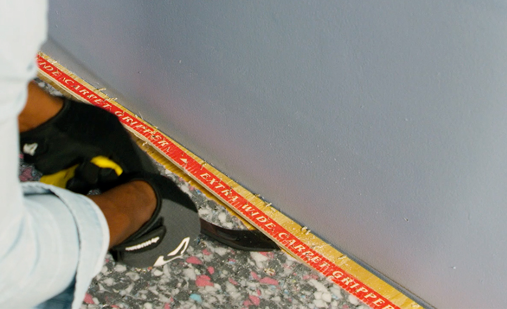 A person using a pry bar to remove carpet tack strips.