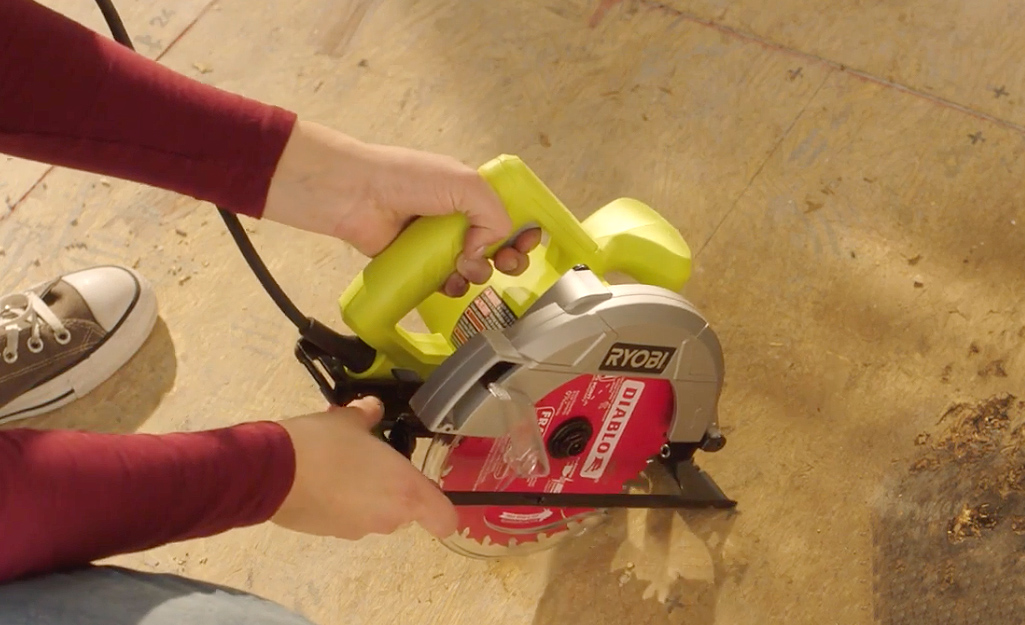 Someone using a circular saw on a wood subfloor.