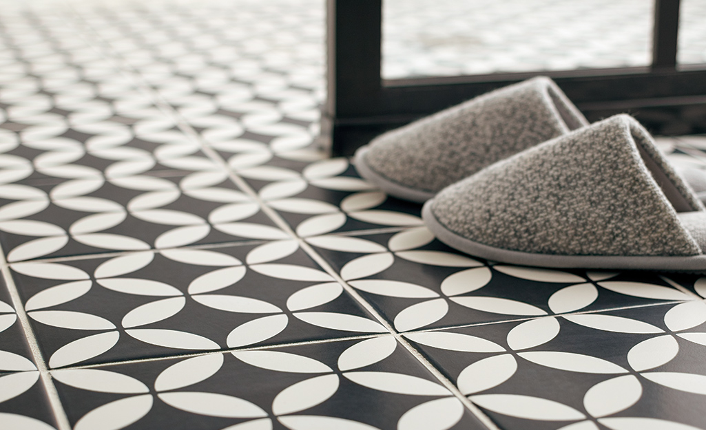 Slippers placed on black and gray bath tile floor.