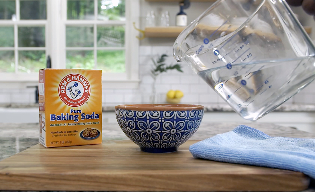 A person mixing baking soda and water to clean glass.