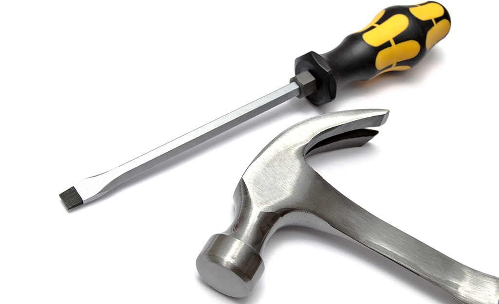 A hammer lying beside a screwdriver.