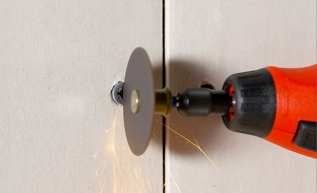 Small saw cutting into a screw in a wall.
