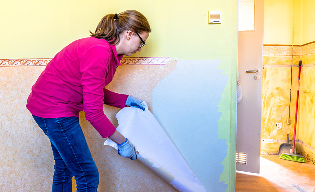 A woman removing wallpaper.