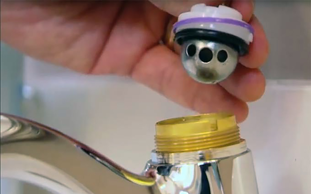 The ball, packing washer and cam assembly is removed from a ball faucet. The ball, packing washer and cam assembly is removed from a ball faucet.