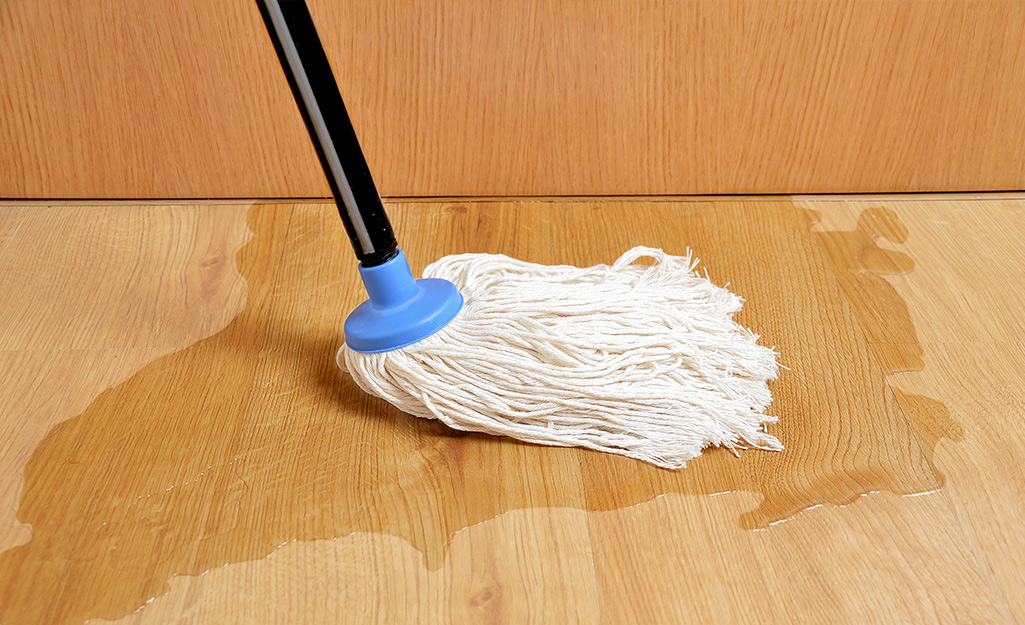 A mop soaks up water from a laminate floor.