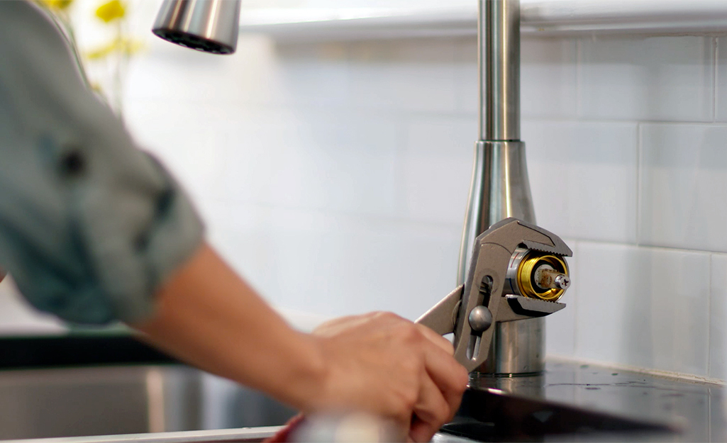 Someone loosening the faucet on a kitchen sink.