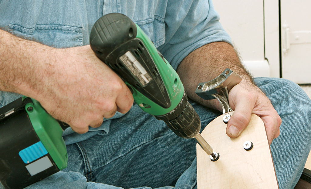 a man installing screws on a new ceiling fan blade