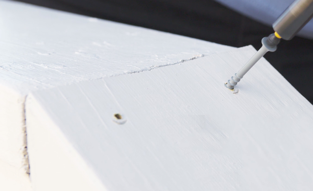 A screw being drilled into a mitered corner of a deck.
