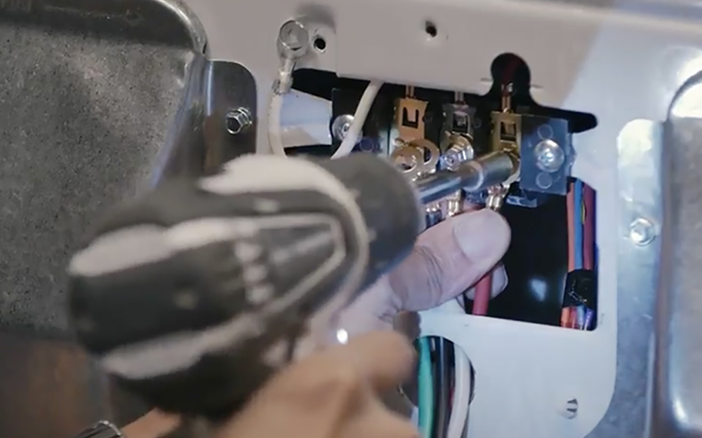 Person using a drill to attach a new dryer cord Person using a drill to attach a new dryer cord
