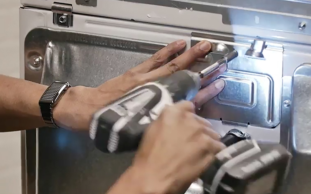Person installing back panel on a dryer. Person installing back panel on a dryer.