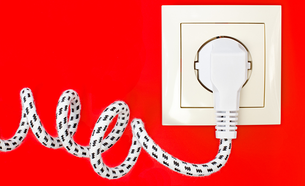 A fabric-covered power cord is plugged into an outlet.