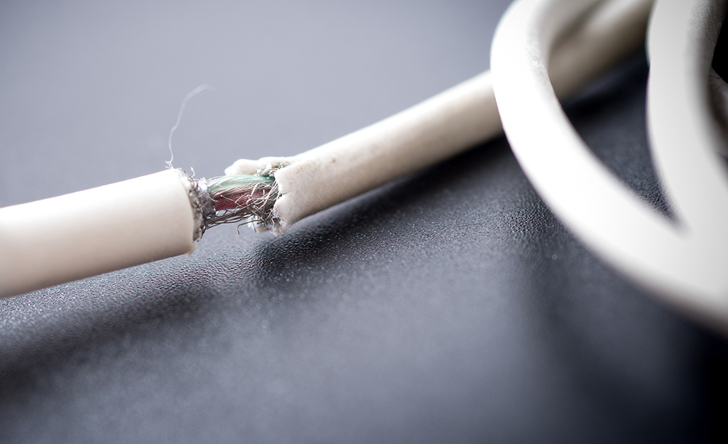 A damaged electrical cord has fully exposed wiring.